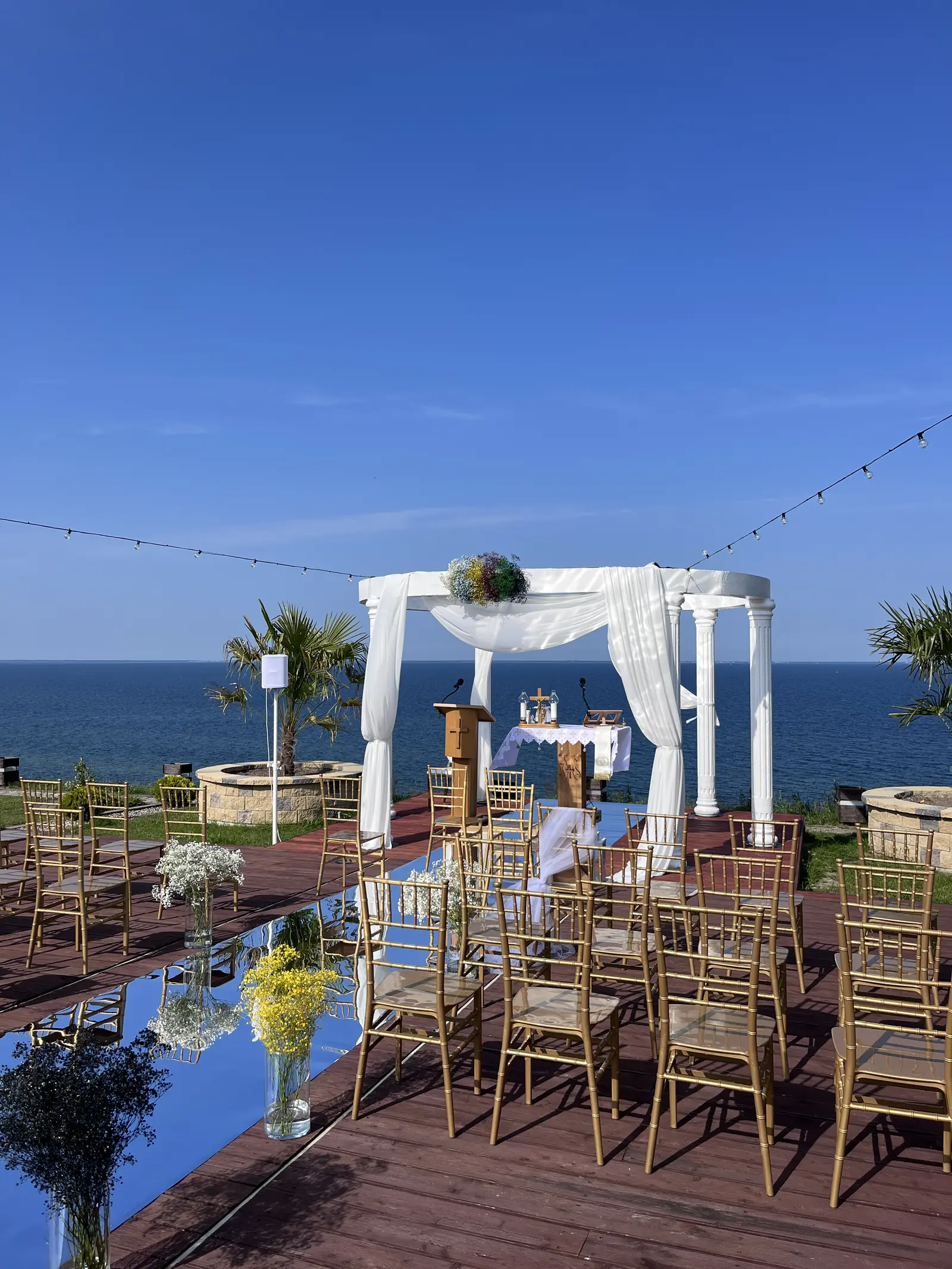 Biała pergola i złote krzesła nad morzem
